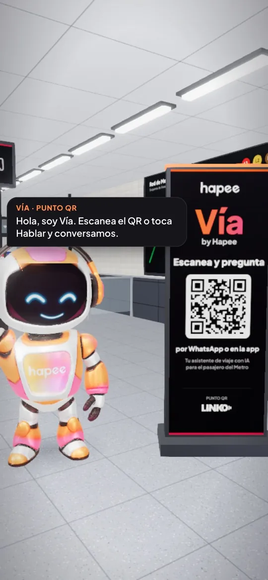 Celular en la estación 3D: el robot del Punto QR saluda junto al tótem de Vía con el código QR.